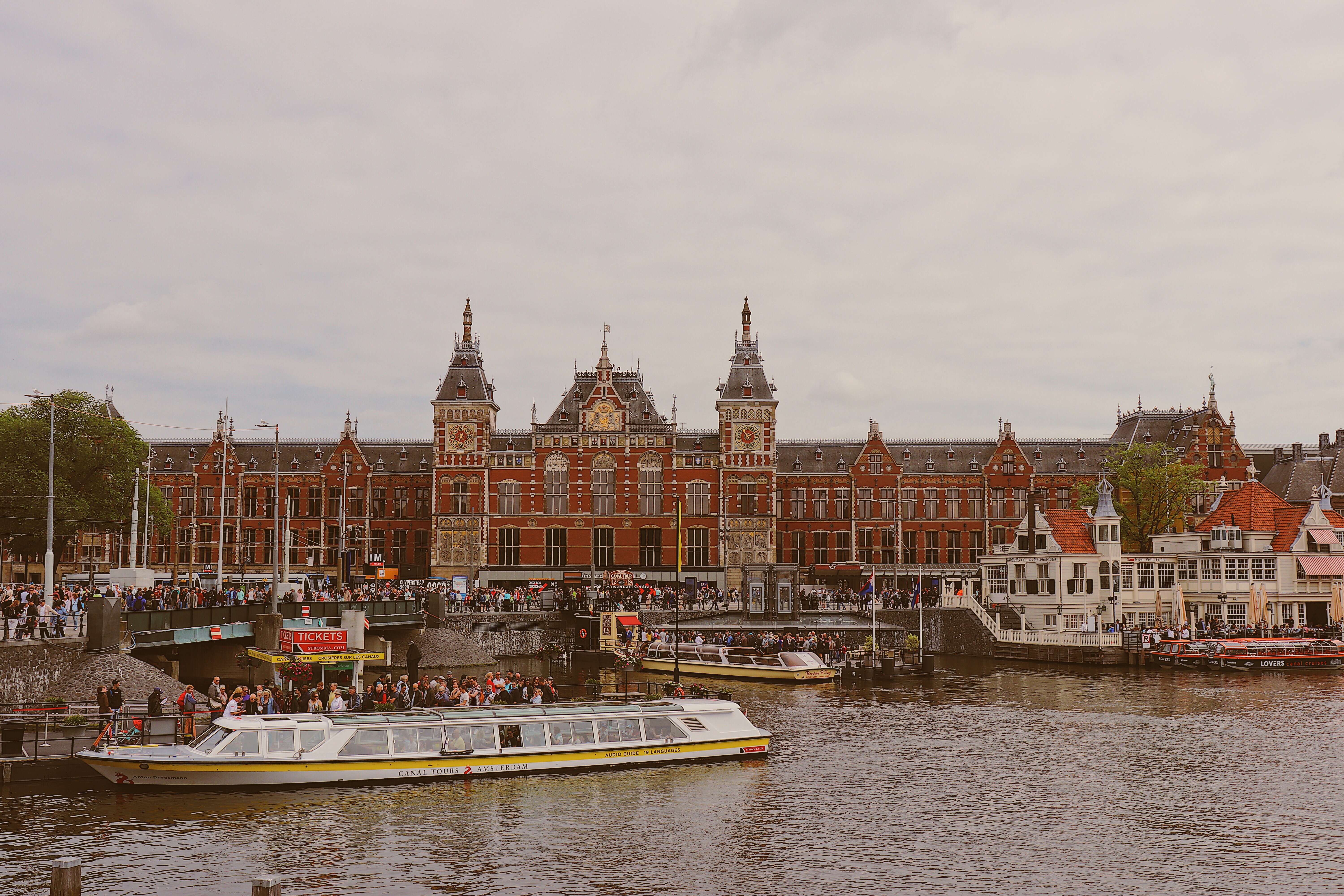 Photo of Amsterdam Centraal with canal boat tours in the water in Amsterdam, Netherlands.
