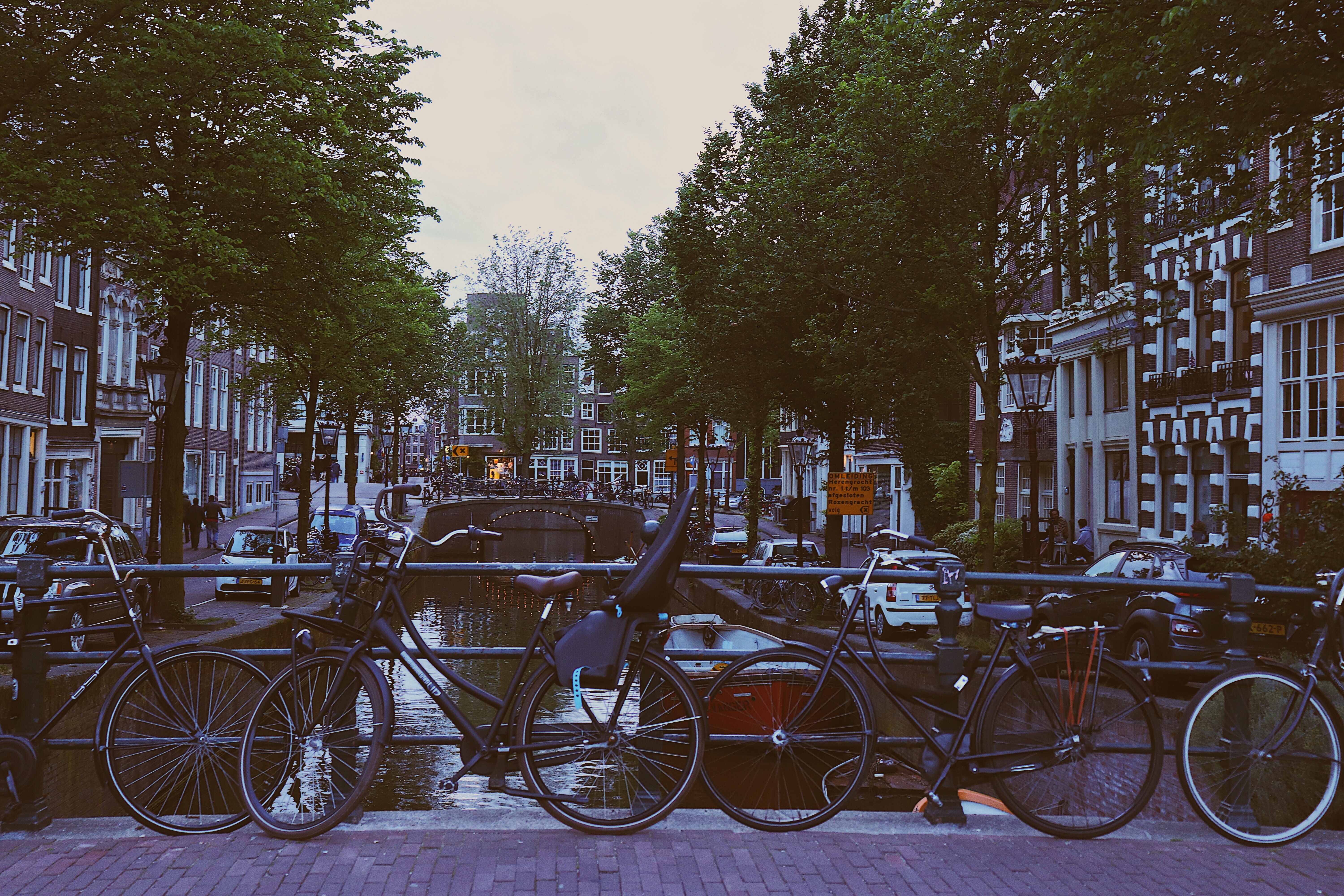 Photo of bikes lined up on one of the bridges over the canals in Amsterdam, Netherlands with Dutch architecture in the backgrounds.