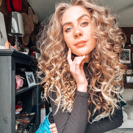 Candace poses with a head of tight ringlet curls in a black turtleneck and stonewash Levi's jeans in her office.